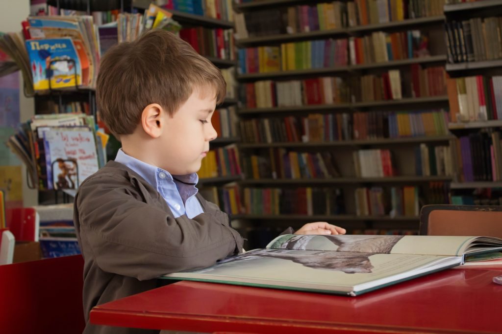 enfant lisant un livre dans une bibliothèque-Marie Duval sophrologue